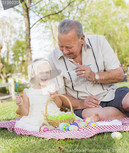 Image of Grandfather and Granddaughter Coloring Easter Eggs on Blanket At