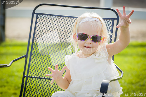 Image of Cute Playful Baby Girl Wearing Sunglasses Outside at Park