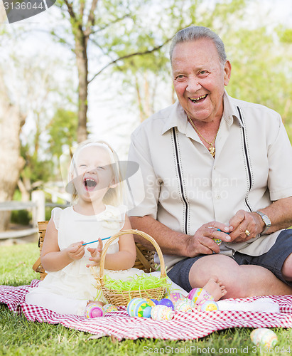 Image of Grandfather and Granddaughter Coloring Easter Eggs on Blanket At