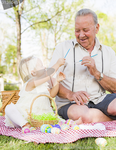 Image of Grandfather and Granddaughter Coloring Easter Eggs on Blanket At