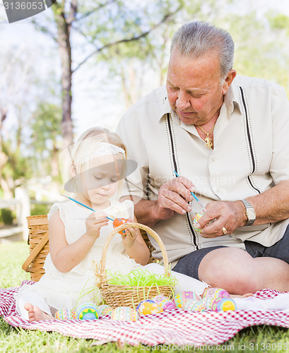 Image of Grandfather and Granddaughter Coloring Easter Eggs on Blanket At