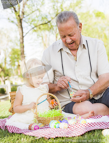 Image of Grandfather and Granddaughter Coloring Easter Eggs on Blanket At