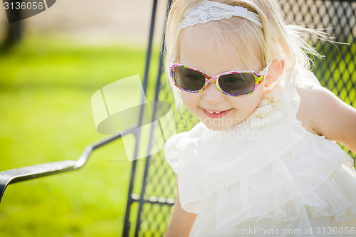 Image of Cute Playful Baby Girl Wearing Sunglasses Outside at Park