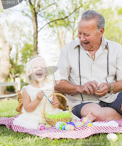 Image of Grandfather and Granddaughter Coloring Easter Eggs on Blanket At