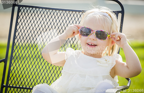 Image of Cute Playful Baby Girl Wearing Sunglasses Outside at Park