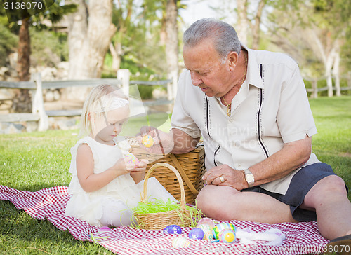 Image of Grandfather and Granddaughter Enjoying Easter Eggs on Blanket At