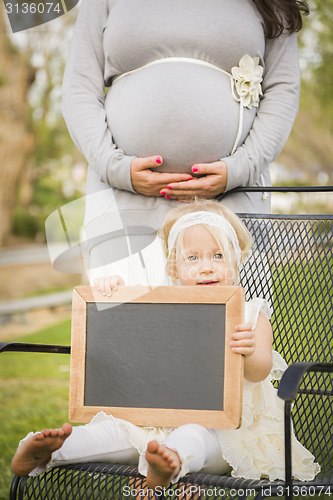 Image of Pregnant Mom Behind Baby Girl in Chair Holding Blank Blackboard