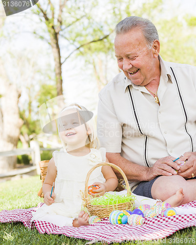 Image of Grandfather and Granddaughter Coloring Easter Eggs on Blanket At