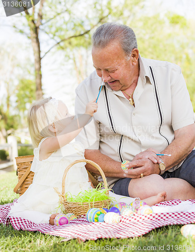 Image of Grandfather and Granddaughter Coloring Easter Eggs on Blanket At