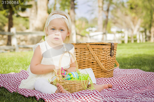 Image of Cute Baby Girl Enjoying Her Easter Eggs on Picnic Blanket