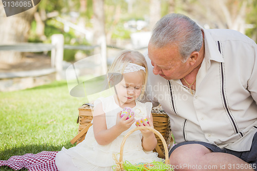 Image of Grandfather and Granddaughter Enjoying Easter Eggs on Blanket At