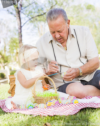 Image of Grandfather and Granddaughter Coloring Easter Eggs on Blanket At