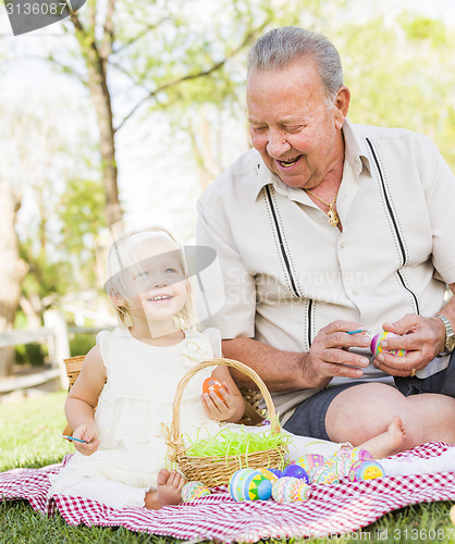 Image of Grandfather and Granddaughter Coloring Easter Eggs on Blanket At