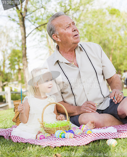 Image of Grandfather and Granddaughter Coloring Easter Eggs on Blanket At