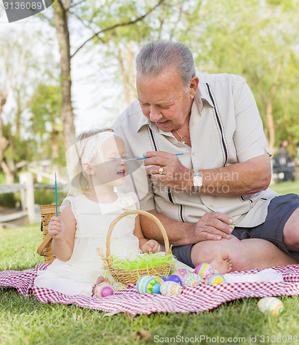 Image of Grandfather and Granddaughter Coloring Easter Eggs on Blanket At