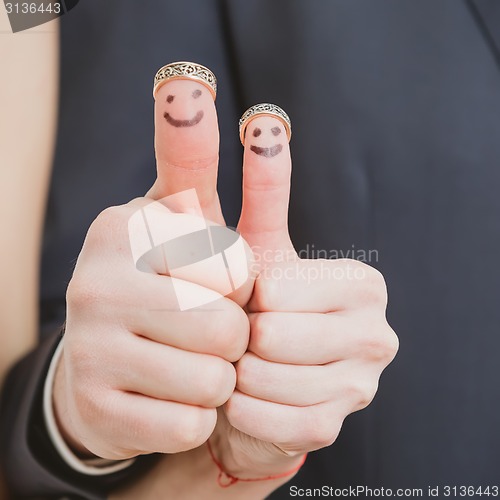 Image of wedding rings on their fingers painted with the bride and groom, funny little people