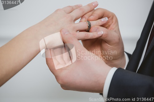 Image of Groom put a ring on finger of his lovely wife.