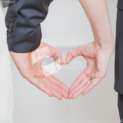 Image of wedding couple showing shape of heart from their hands.