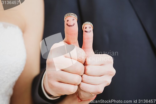 Image of wedding rings on their fingers painted with the bride and groom, funny little people