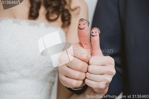 Image of wedding rings on their fingers painted with the bride and groom, funny little people