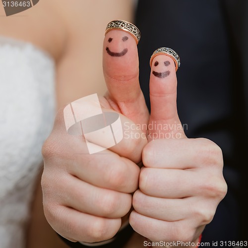 Image of wedding rings on their fingers painted with the bride and groom, funny little people