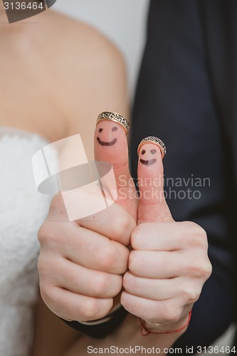 Image of wedding rings on their fingers painted with the bride and groom, funny little people