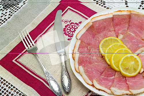 Image of The dish with slices of ham and lemon 
