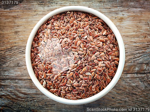 Image of Bowl of flax seeds on old wooden table