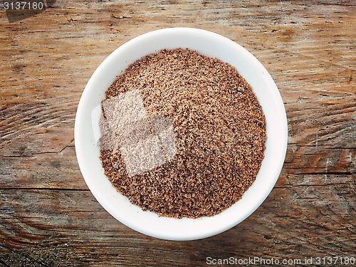 Image of Bowl of crushed flax seeds on old wooden table