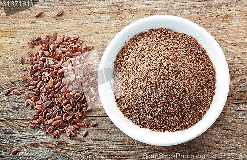 Image of Bowl of crushed flax seeds on old wooden table