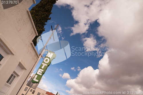 Image of Neon Motel Sign Clear Blue Sky White Billowing Clouds