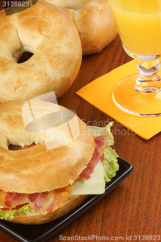 Image of Bagel with bacon, cheese and lettuce and orange juice