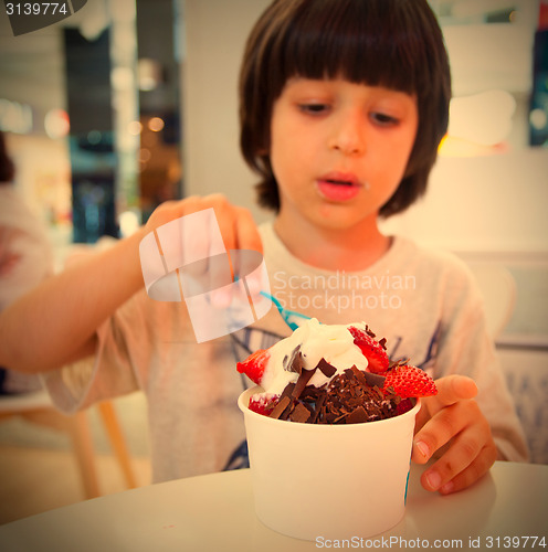 Image of boy eating ice cream with chocolate and strawberries