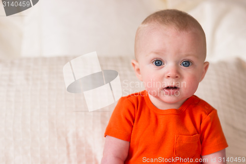 Image of Young Blue Eyed Infant Boy Sitting up Looking at Camera