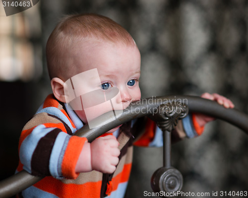 Image of Infant Boy Blue Eyes Biting Wrought Iron Headboard