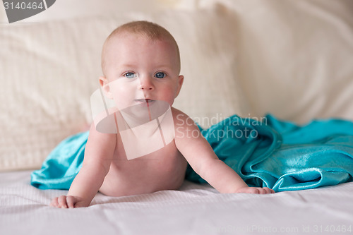 Image of Young Blue Eyed Infant Boy Laying on Bed Looking 