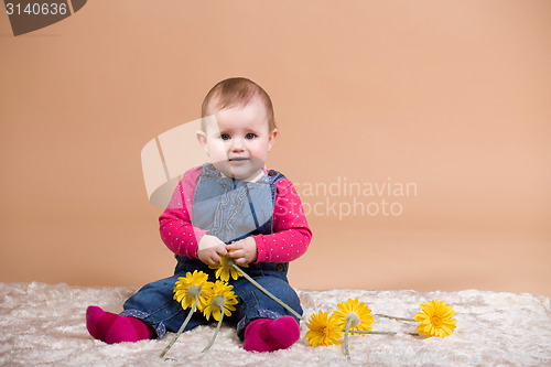 Image of smiling infant baby with yellow flowers