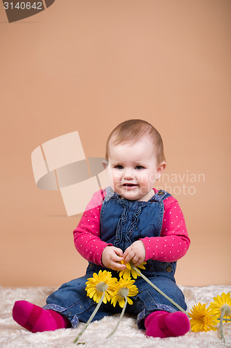 Image of smiling infant baby with yellow flowers