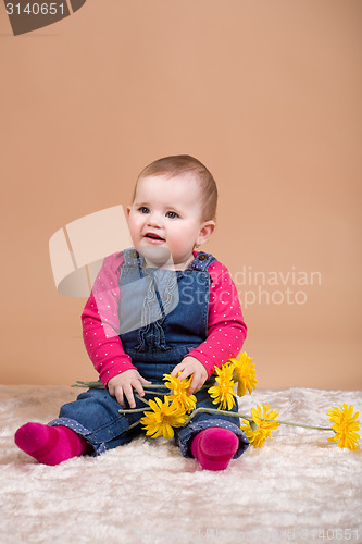 Image of smiling infant baby with yellow flowers