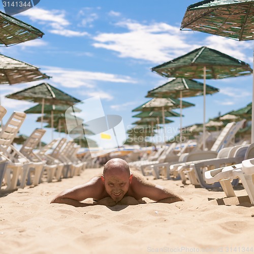 Image of Half face of a handsome man covered with sand