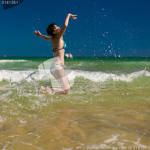 Image of woman splashing water in the ocean