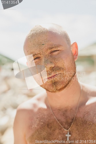 Image of Half face of a handsome man covered with sand