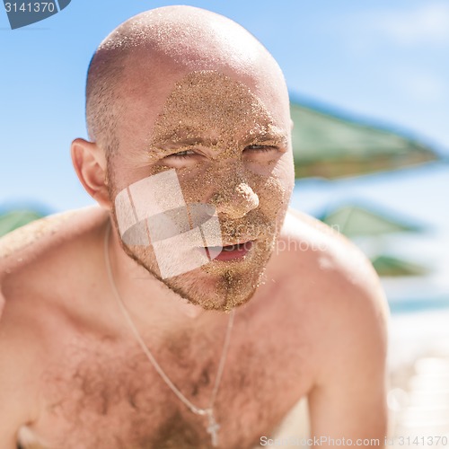 Image of Half face of a handsome man covered with sand