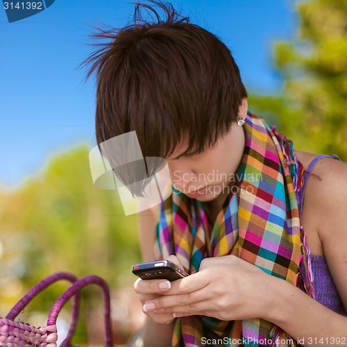 Image of Young beautiful woman writes an SMS