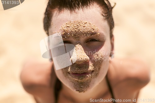 Image of Beautiful girl with sand on face