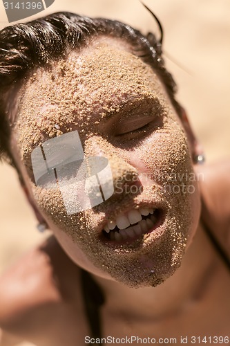 Image of Beautiful girl with sand on face