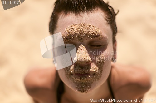 Image of Beautiful girl with sand on face