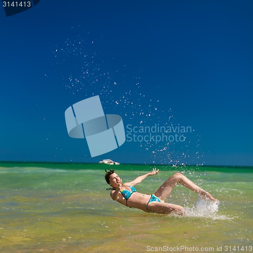 Image of woman splashing water in the ocean