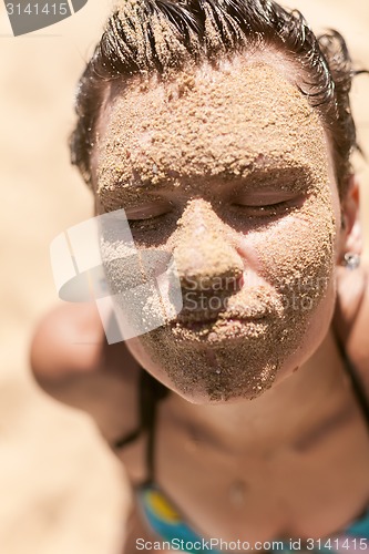 Image of Beautiful girl with sand on face