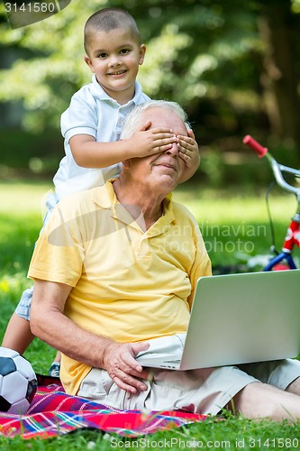 Image of grandfather and child using laptop